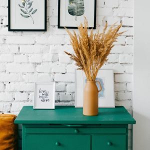Blue-green console table against a white brick wall