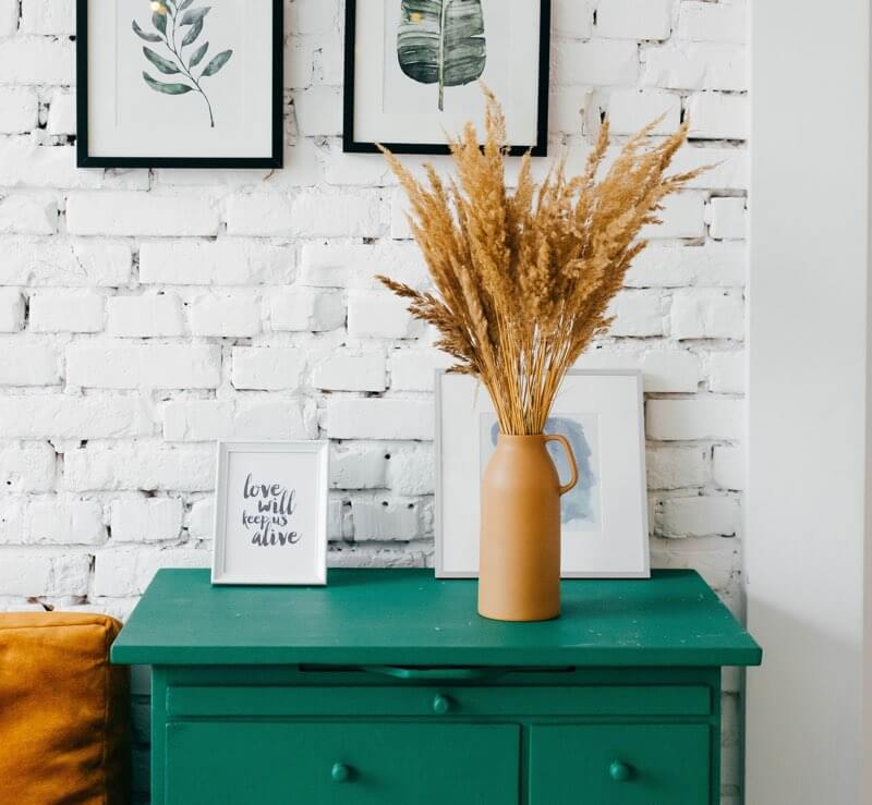 Blue-green console table against a white brick wall