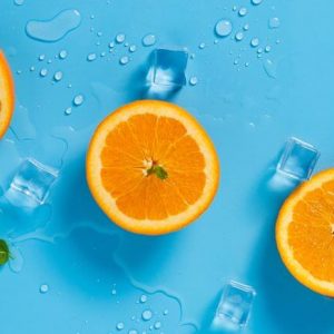 Cut oranges on a sky blue background and ice cubes