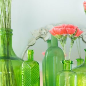 Green glass bottles with coral carnations