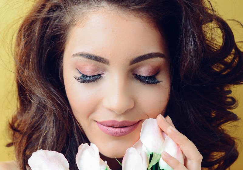 Woman with makeup smelling flowers