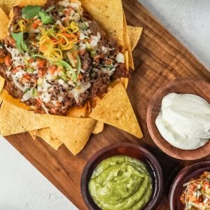 Nachos with guacamole and sour cream on a platter