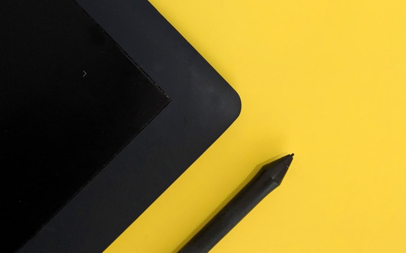 Digital tablet with digital pen on yellow background