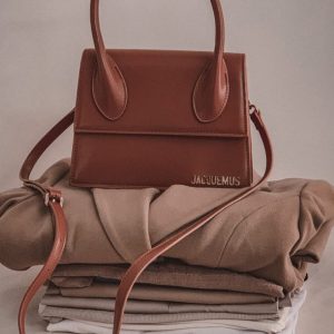 Brown handbag placed on folded clothes - winter/autumn colors